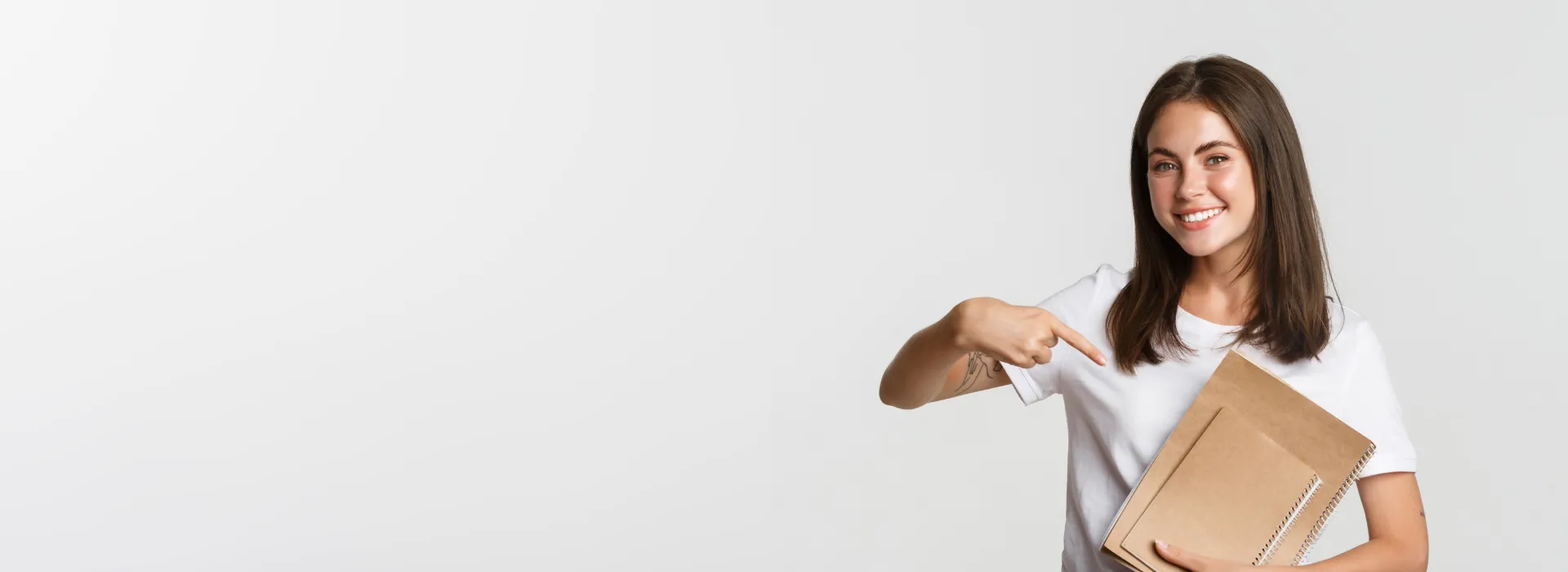 Teenage girl holding books and pointing to orthodontics.