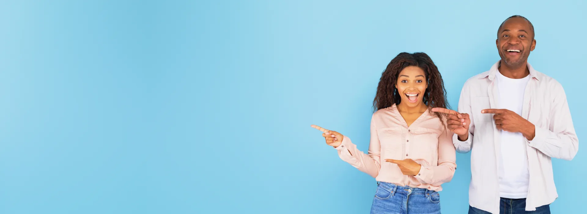 Happy couple pointing at orthodontics on blue background.